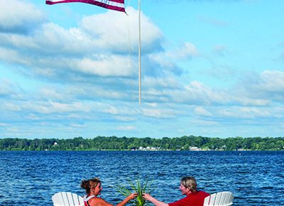 A couple sharing a bottle of wine on a dock along the shore of Cayuga Lake
