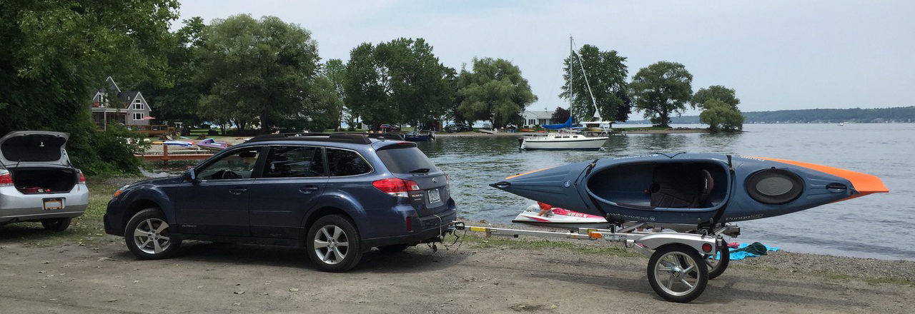 Getting Ready To Launch Kayaks At Sheldrake Point Park photo of car towing a trailer with two kayaks one blue one orangeGetting Ready To Launch Kayaks At Sheldrake Point Park