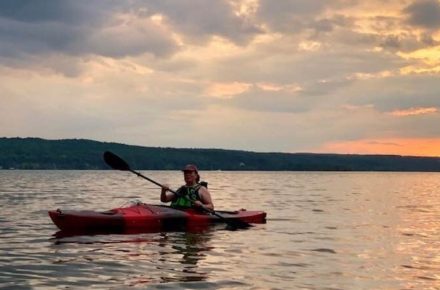 Kayaker paddling on Cayuga Lake at sunset